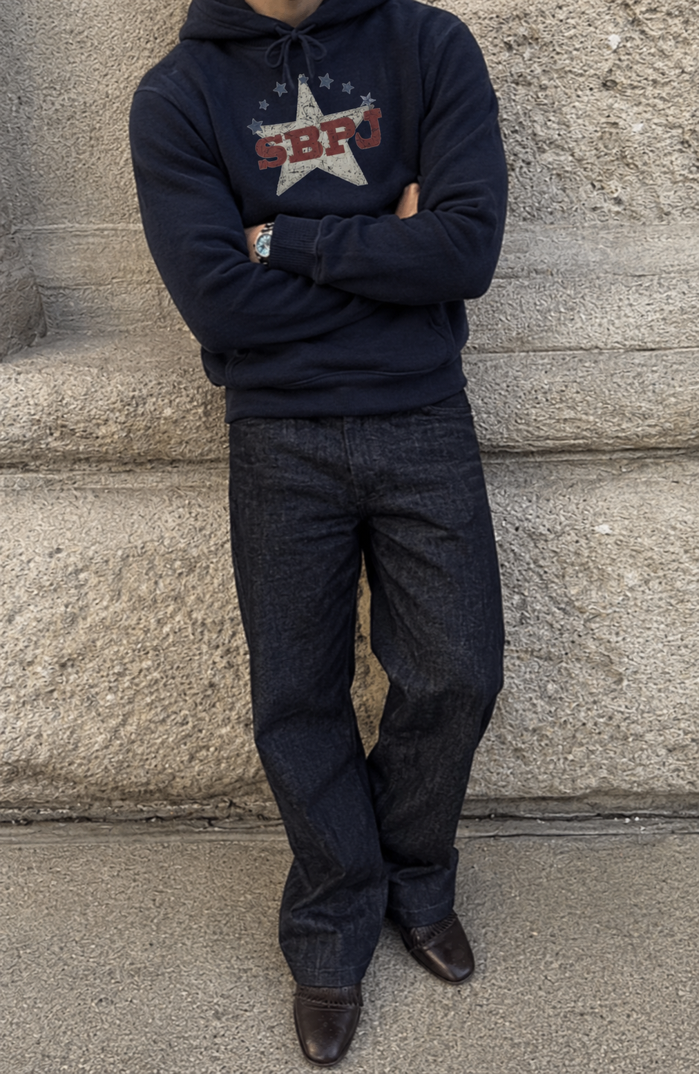 Relaxed streetstyle in a navy Empire Noire hoodie by a stone wall